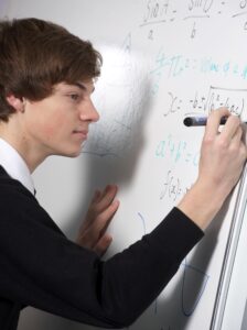 A school student writing on a whiteboard