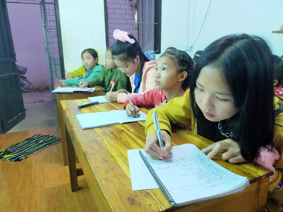 Pupils in a classroom holding their hands up