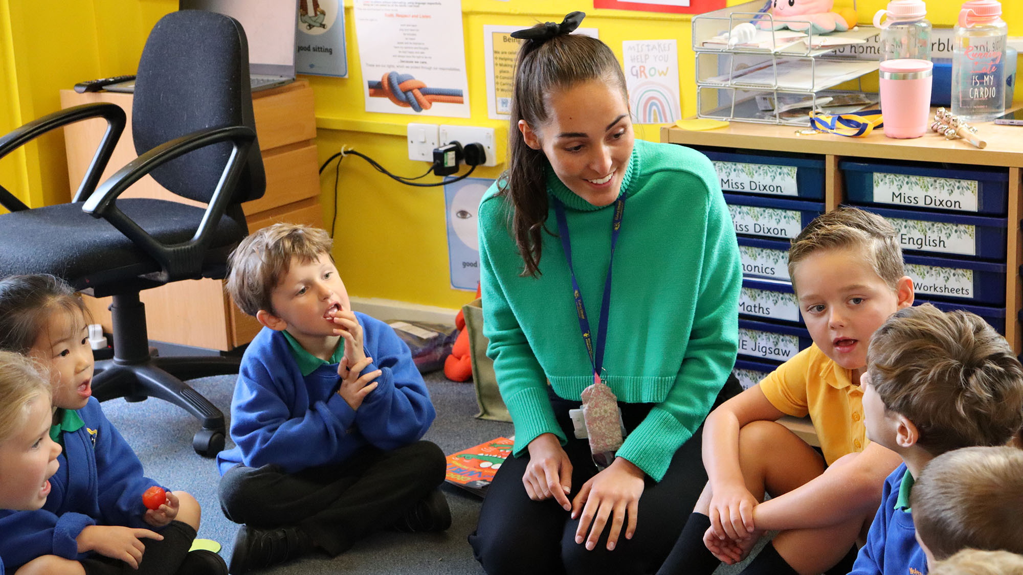 Pupils in a classroom holding their hands up